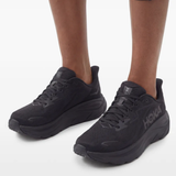 Black sneakers worn by a person, showing the sneakers' fit