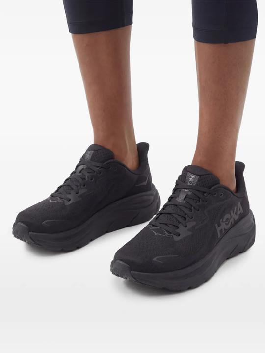 Black sneakers worn by a person, showing the sneakers' fit