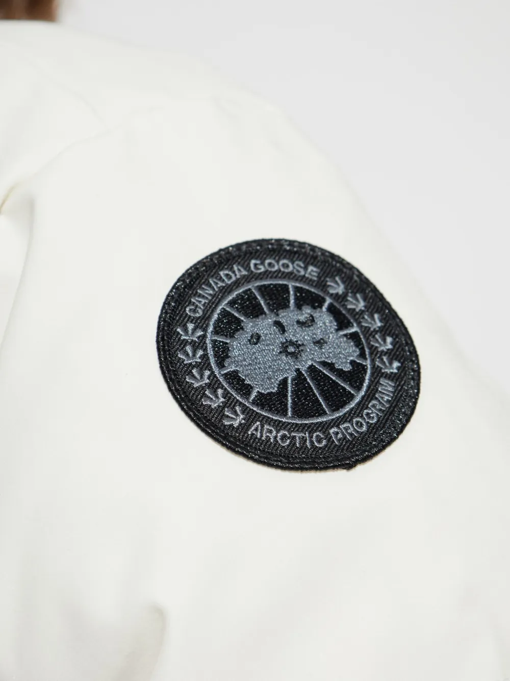 Close up of white jacket,showing texture of the recycled polyester fabric.