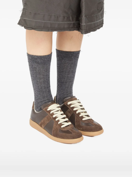 Brown sneakers worn by a person, showing the sneakers's fit