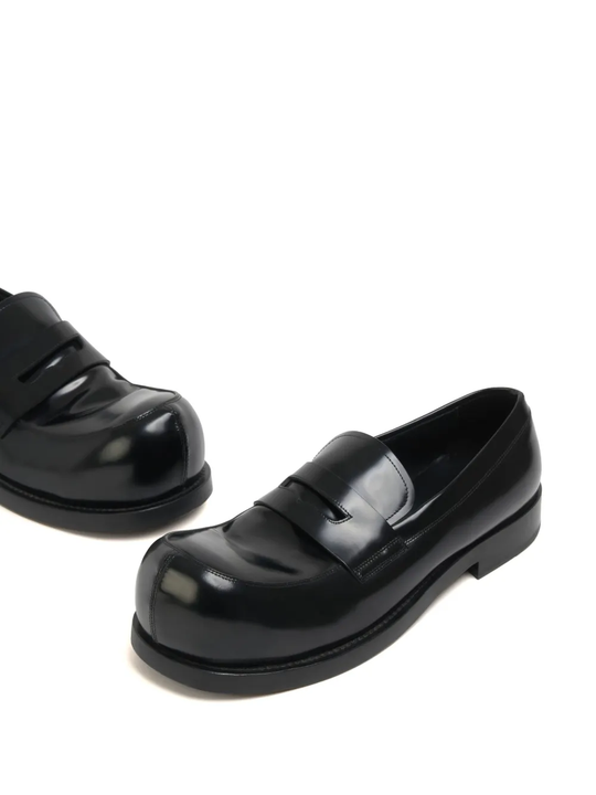 Close up of the black loafer, showing texture of the leather fabric