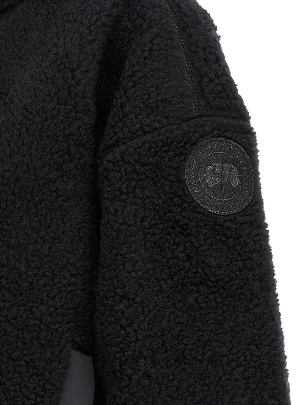 Close up of black jackets, showing texture of the wool and polyester fabric