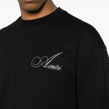 Black t-shirt with 'Amiri' logo worn by a person on a white background