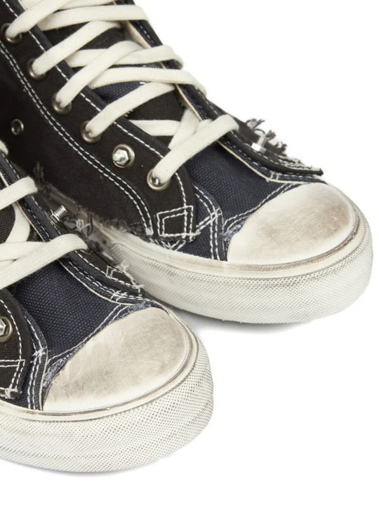 Close up of black sneakers, showing texture of the cotton and rubber and goat leather fabric