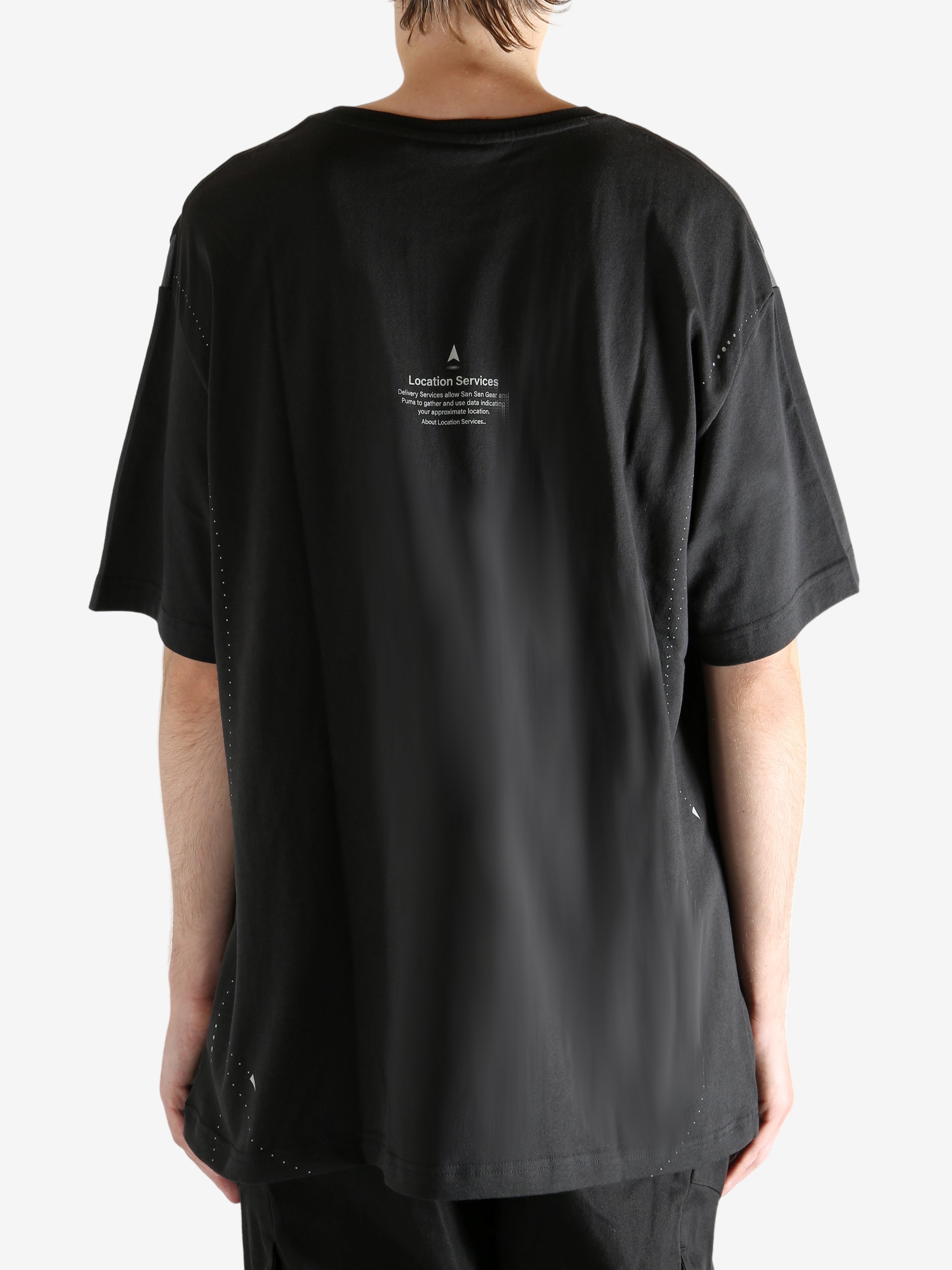 Black tee worn by a person, showing the tee"s fit