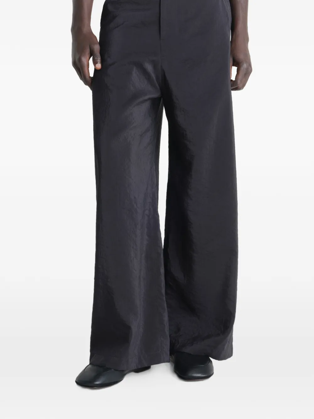 Black slipper worn by a person, showing the casual fit