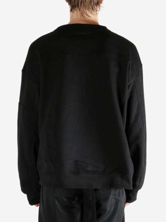 Black sweater worn by a person, showing the sweater's fit
