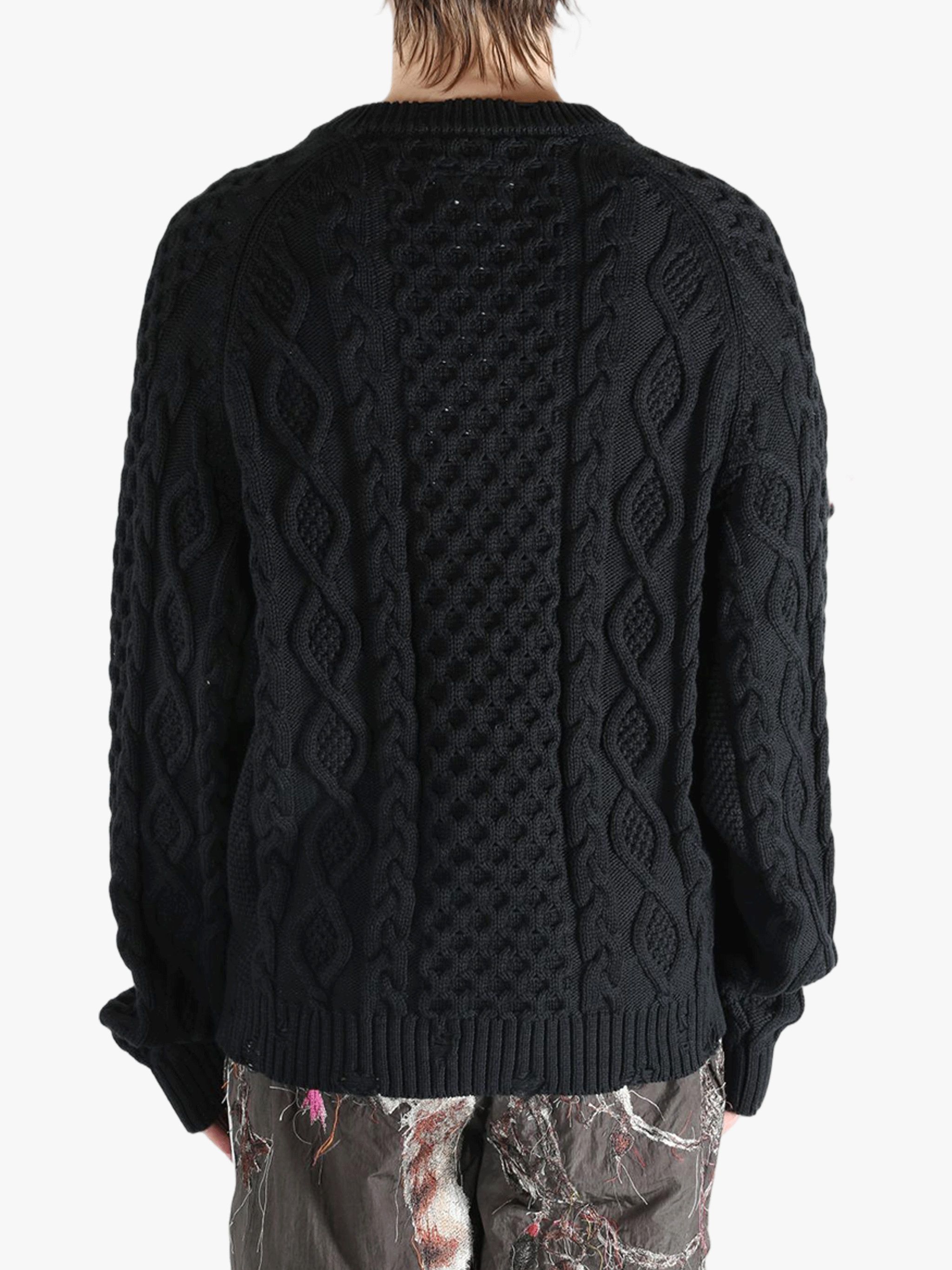 Black knitwear worn by a person, showing the knitwear's fit