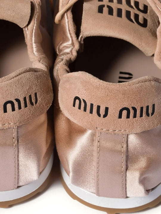 Close up of pink sneakers, showing texture of the rubber and satin calf suede fabric