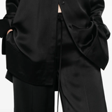 Close up of black pants, showing the detail of the strap on waist