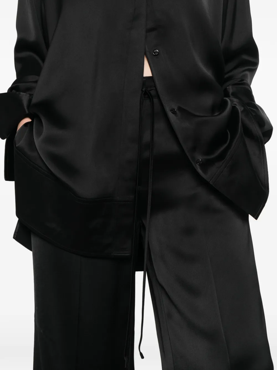 Close up of black pants, showing the detail of the strap on waist