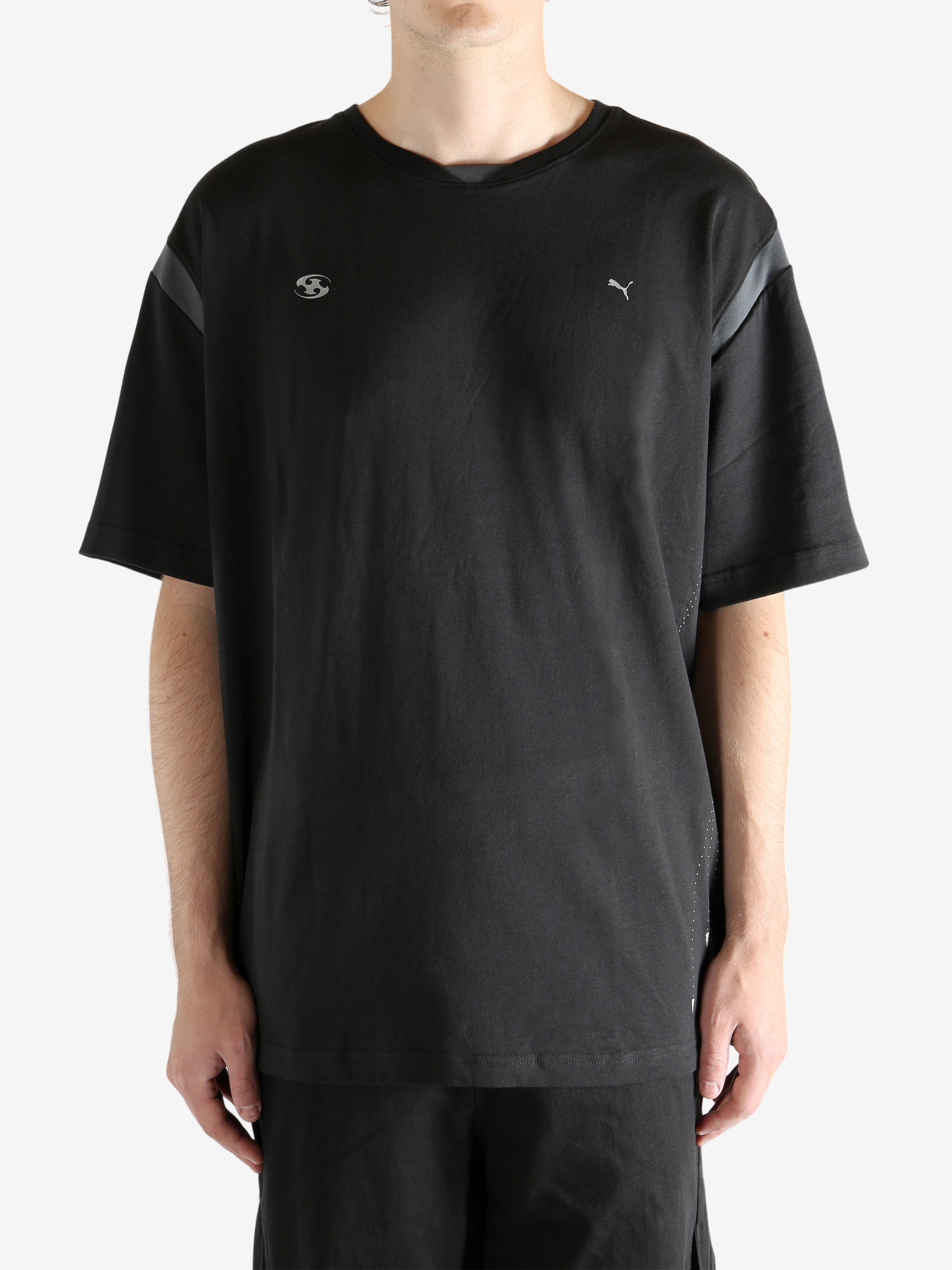 Black tee worn by a person, showing the tee"s fit