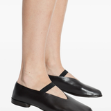 Black leather shoes worn with tights on a white background
