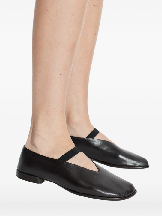 Black leather shoes worn with tights on a white background