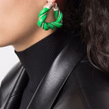 Green earrings worn by a person, showing the earrings fit